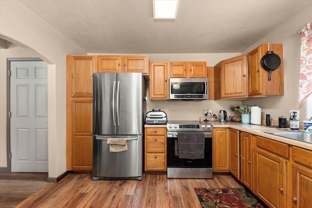 1481 Northshore Diamond Lake Rd, Newport, WA 99156 - kitchen with stainless steel appliances, wood finished floors, arched walkways, and light countertops