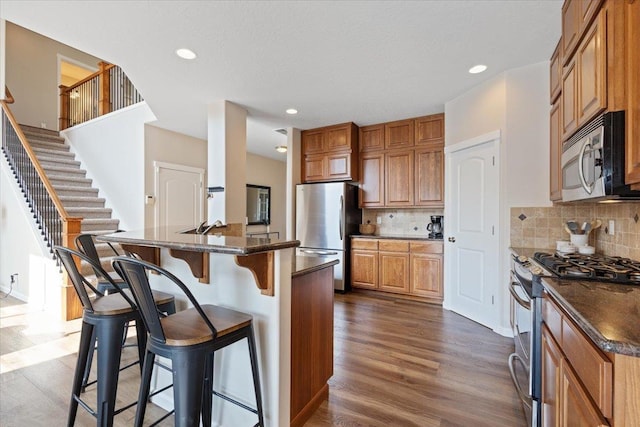 4213 S Cook St, Spokane, WA 99223 - kitchen with appliances with stainless steel finishes, a breakfast bar, dark wood-style floors, backsplash, and recessed lighting