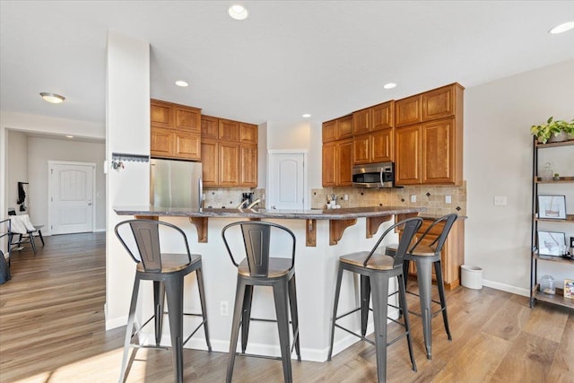 4213 S Cook St, Spokane, WA 99223 - kitchen with appliances with stainless steel finishes, tasteful backsplash, light wood-style floors, recessed lighting, and a kitchen bar