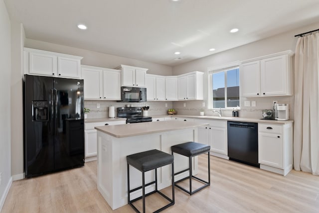 1248 W Staples Rd, Post Falls, ID 83854 - kitchen featuring black appliances, backsplash, white cabinets, light countertops, and a center island