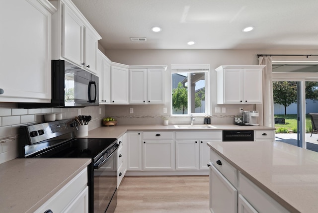 1248 W Staples Rd, Post Falls, ID 83854 - kitchen featuring range with electric stovetop, black microwave, healthy amount of natural light, white cabinetry, and recessed lighting