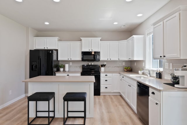1248 W Staples Rd, Post Falls, ID 83854 - kitchen with black appliances, light wood-style floors, a center island, decorative backsplash, and recessed lighting