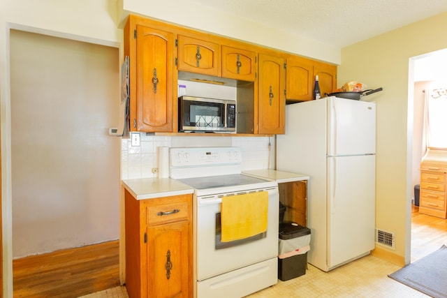 5711 N Ash St, Spokane, WA 99205 - kitchen featuring white appliances, tasteful backsplash, light countertops, and brown cabinetry