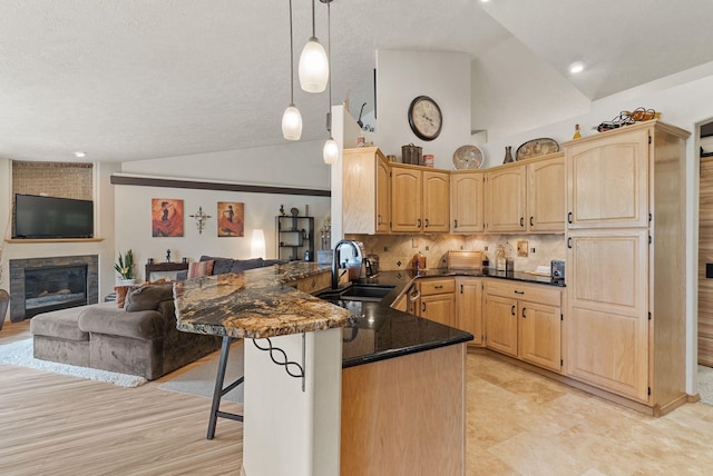 4812 S Wildwood Ln, Spokane, WA 99206 - kitchen featuring light brown cabinetry, a peninsula, a kitchen breakfast bar, open floor plan, and a textured ceiling