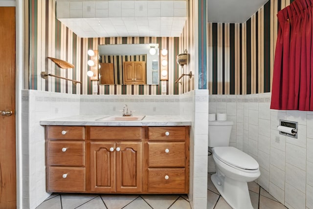14807 E Broadway Ave, Spokane Valley, WA 99216 - bathroom with wallpapered walls, tile patterned floors, tile walls, vanity, and wainscoting