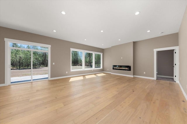6571 Kate Dr, Nine Mile Falls, WA 99206 - unfurnished living room featuring healthy amount of natural light, light wood-type flooring, recessed lighting, and a glass covered fireplace