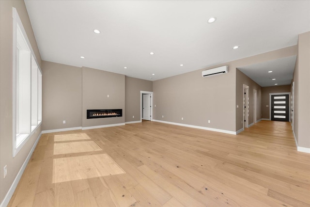 6571 Kate Dr, Nine Mile Falls, WA 99206 - unfurnished living room featuring a wall mounted AC, light wood-type flooring, recessed lighting, and a glass covered fireplace