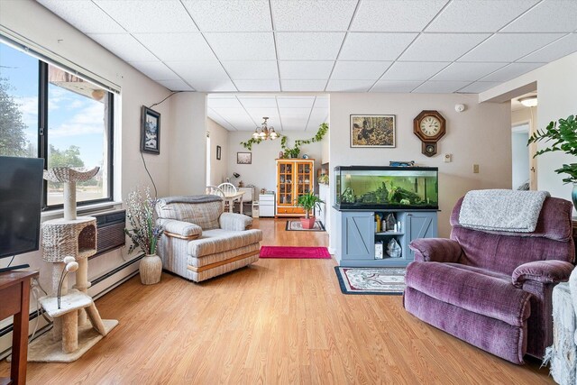 1716 N Pettet Dr Apt 2, Spokane, WA 99205 - living area with wood finished floors, a drop ceiling, healthy amount of natural light, a chandelier, and baseboard heating