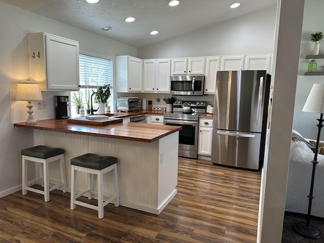 1612 E Sharpsburg Ave, Spokane, WA 99217 - kitchen featuring wooden counters, stainless steel appliances, recessed lighting, dark wood-type flooring, and a peninsula