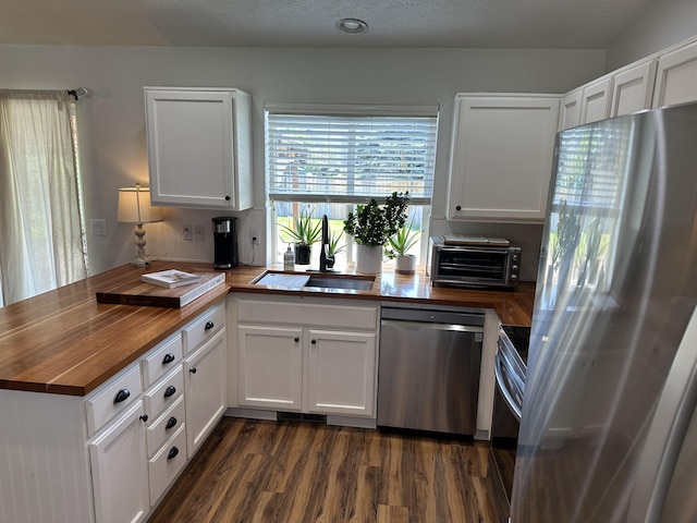 1612 E Sharpsburg Ave, Spokane, WA 99217 - kitchen with stainless steel appliances, butcher block counters, a peninsula, and dark wood finished floors