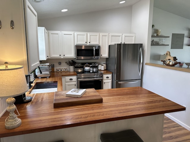 1612 E Sharpsburg Ave, Spokane, WA 99217 - kitchen with butcher block counters, stainless steel appliances, lofted ceiling, white cabinetry, and a peninsula
