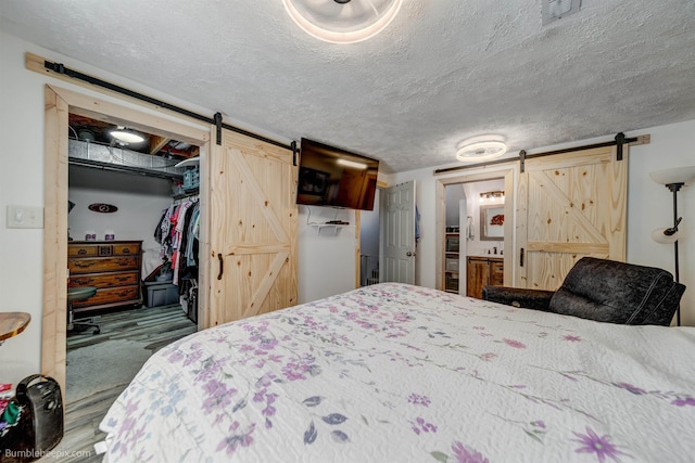 1612 E Sharpsburg Ave, Spokane, WA 99217 - bedroom with a barn door, a textured ceiling, and a walk in closet