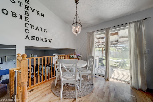 1612 E Sharpsburg Ave, Spokane, WA 99217 - dining area featuring lofted ceiling, a textured ceiling, wood finished floors, and a chandelier