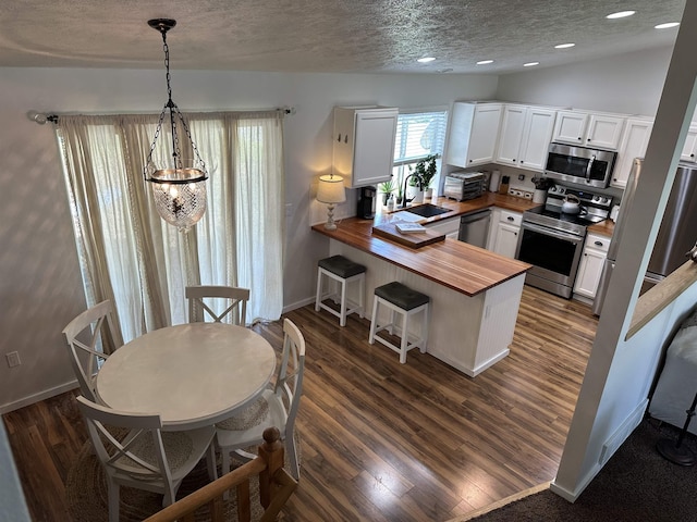 1612 E Sharpsburg Ave, Spokane, WA 99217 - kitchen featuring appliances with stainless steel finishes, wood counters, a textured ceiling, a peninsula, and white cabinetry