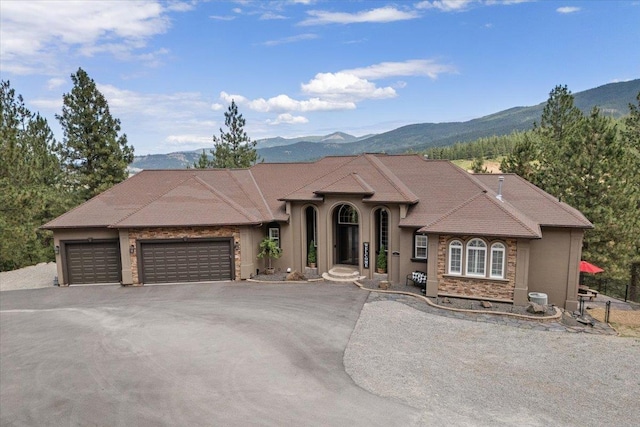 7105 S Saddle Ridge Ln, Spokane Valley, WA 99016 - view of front of home with a mountain view, an attached garage, stone siding, and driveway