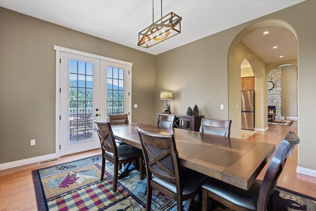 7105 S Saddle Ridge Ln, Spokane Valley, WA 99016 - dining space featuring light wood-style floors, arched walkways, french doors, a stone fireplace, and recessed lighting
