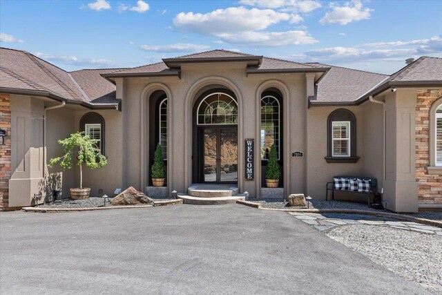 7105 S Saddle Ridge Ln, Spokane Valley, WA 99016 - doorway to property with stone siding, stucco siding, and roof with shingles