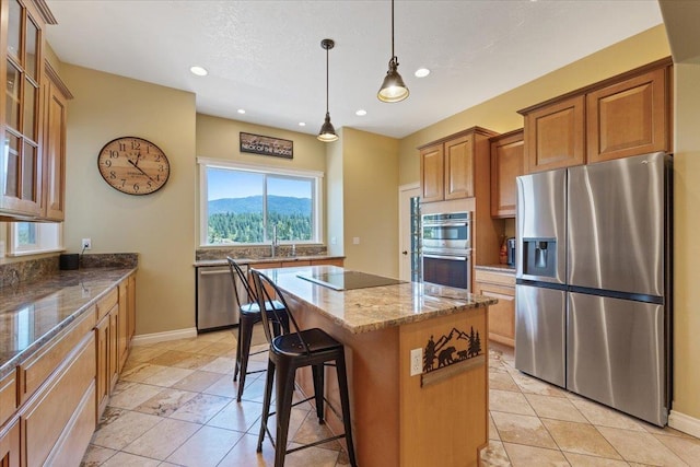 7105 S Saddle Ridge Ln, Spokane Valley, WA 99016 - kitchen with appliances with stainless steel finishes, a kitchen island, stone counters, a kitchen bar, and brown cabinetry