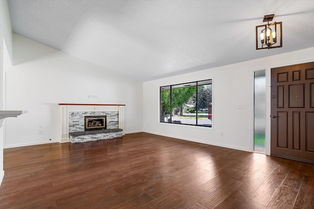 317 E Eaton Ave, Spokane, WA 99218 - unfurnished living room featuring vaulted ceiling, wood finished floors, a chandelier, and a stone fireplace