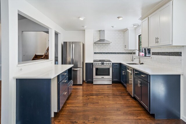 317 E Eaton Ave, Spokane, WA 99218 - kitchen featuring wall chimney exhaust hood, stainless steel appliances, decorative backsplash, light countertops, and dark wood-style flooring