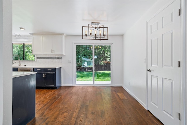 317 E Eaton Ave, Spokane, WA 99218 - kitchen with light countertops, a chandelier, dark wood finished floors, white cabinetry, and tasteful backsplash