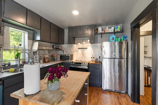 2624 E Boone Ave, Spokane, WA 99202 - kitchen with stainless steel appliances, open shelves, butcher block counters, decorative backsplash, and wood finished floors