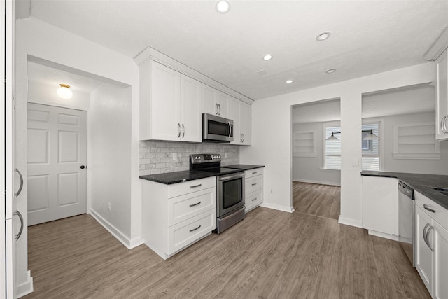 215 E 18th Ave, Spokane, WA 99203 - kitchen featuring appliances with stainless steel finishes, dark countertops, light wood-style floors, white cabinets, and recessed lighting