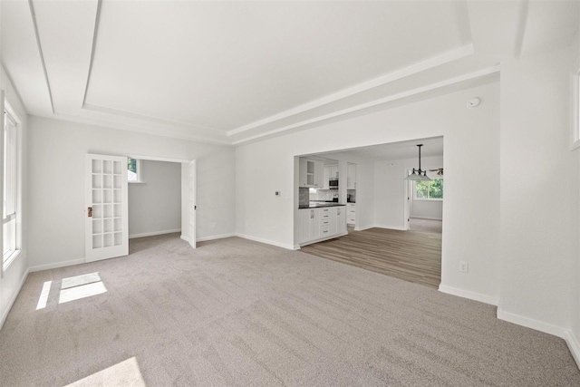 215 E 18th Ave, Spokane, WA 99203 - unfurnished living room featuring a tray ceiling, plenty of natural light, and light colored carpet