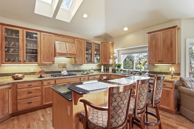 6815 S Palouse Hwy, Spokane, WA 99223 - kitchen with tasteful backsplash, a skylight, a kitchen island, light wood-style floors, and high vaulted ceiling