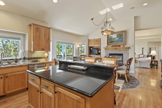 6815 S Palouse Hwy, Spokane, WA 99223 - kitchen featuring open floor plan, a tiled fireplace, light wood-style floors, dark stone countertops, and a center island