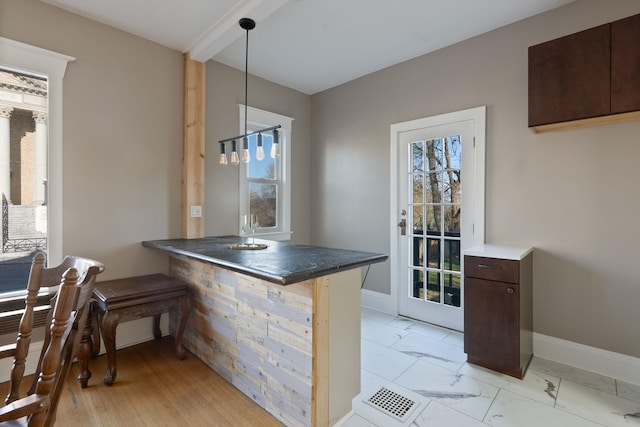 1434 W 8th Ave, Spokane, WA 99204 - kitchen with dark countertops, hanging light fixtures, a peninsula, dark brown cabinetry, and beam ceiling