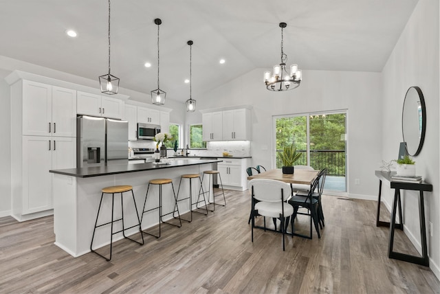 826 Thomas Ln, Newport, WA 99156 - kitchen featuring appliances with stainless steel finishes, a kitchen island with sink, dark countertops, white cabinets, and a breakfast bar area