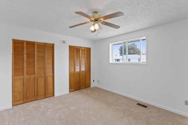 4523 N Royal Ct, Spokane, WA 99205 - unfurnished bedroom featuring multiple closets, a textured ceiling, light colored carpet, and a ceiling fan