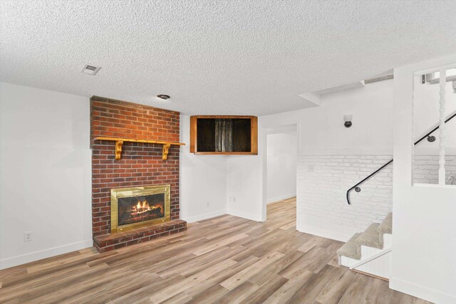 4523 N Royal Ct, Spokane, WA 99205 - unfurnished living room with a textured ceiling, stairway, wood finished floors, a fireplace, and brick wall