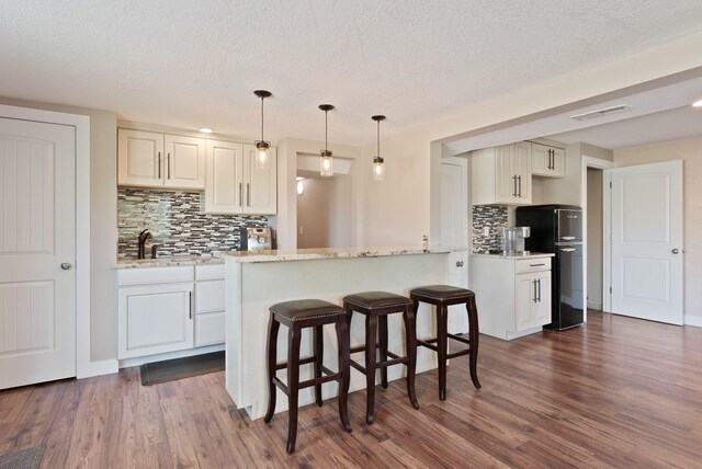 6221 N Highview Ln, Spokane Valley, WA 99217 - kitchen featuring freestanding refrigerator, tasteful backsplash, dark wood-style flooring, a textured ceiling, and a kitchen breakfast bar