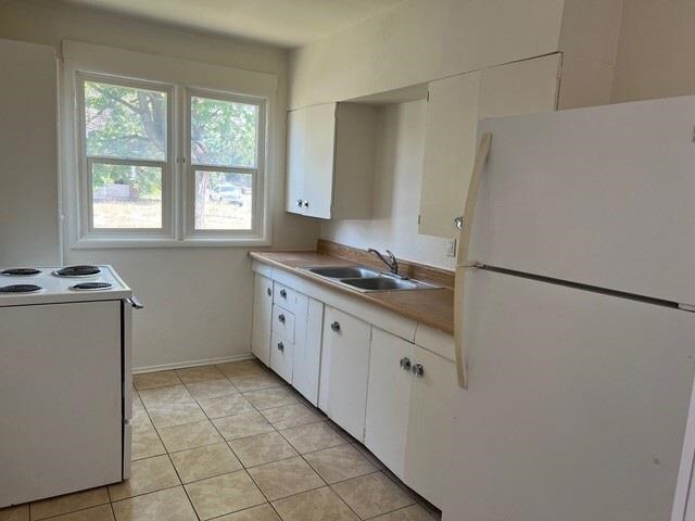 1304 W Maxwell Ave, Spokane, WA 99201 - kitchen with white appliances, white cabinets, light tile patterned floors, and light countertops