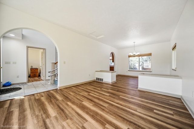 706 S Shelley Lake Ln, Veradale, WA 99037 - unfurnished living room with arched walkways, wood finished floors, and a chandelier