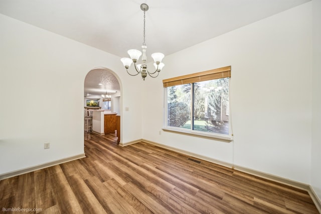 706 S Shelley Lake Ln, Veradale, WA 99037 - spare room featuring a chandelier, arched walkways, and wood finished floors