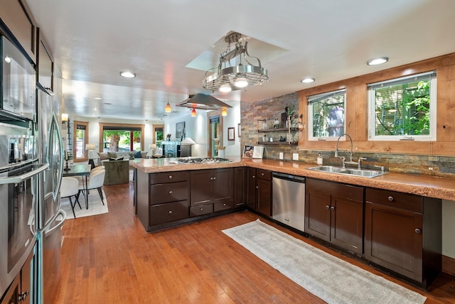 1420 W Main Ave, Spokane, WA 99201 - kitchen with appliances with stainless steel finishes, a peninsula, dark brown cabinets, light wood-style floors, and decorative backsplash