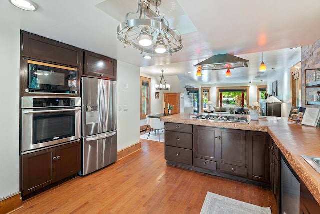 1420 W Main Ave, Spokane, WA 99201 - kitchen with appliances with stainless steel finishes, a chandelier, dark brown cabinets, and light wood-type flooring