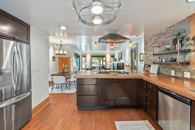 1420 W Main Ave, Spokane, WA 99201 - kitchen with stainless steel appliances, a chandelier, a peninsula, dark brown cabinets, and wood finished floors