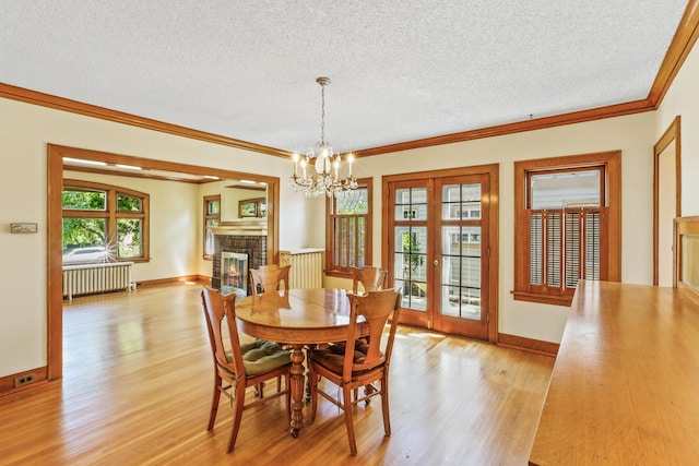 1107 W 19th Ave, Spokane, WA 99203 - dining space with radiator, light wood-style floors, a textured ceiling, a fireplace, and ornamental molding