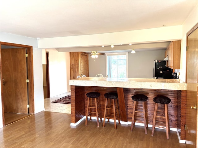 8602 E E Harrington Ave, Spokane Valley, WA 99212 - kitchen featuring freestanding refrigerator, a kitchen bar, light countertops, light wood finished floors, and a peninsula