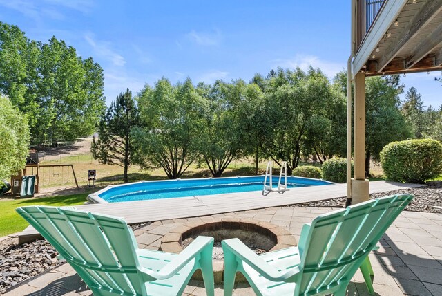 5857 Little Sandy Loop Rd, Nine Mile Falls, WA 99026 - outdoor pool featuring a fire pit, a patio area, and view of wooded area