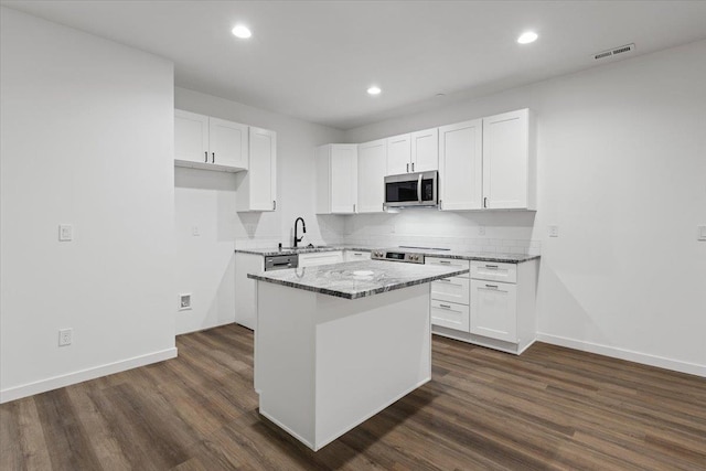 2236 E 4th Ave, Spokane, WA 99202 - kitchen featuring appliances with stainless steel finishes, dark wood finished floors, a center island, white cabinets, and recessed lighting