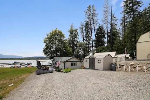 23632 E Beach Ln, Newman Lake, WA 99025 - view of front of home with a storage shed, driveway, a water view, and a patio area