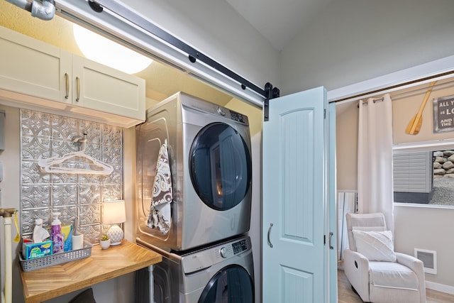 23632 E Beach Ln, Newman Lake, WA 99025 - washroom with stacked washer and clothes dryer, a barn door, and wood finished floors