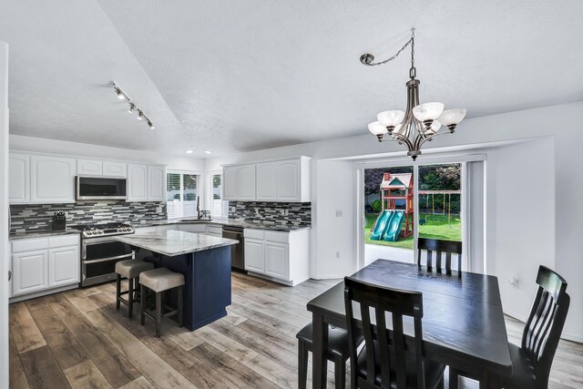 1308 S Drummond Rd, Spokane Valley, WA 99016 - kitchen featuring stainless steel appliances, a textured ceiling, a kitchen island, white cabinets, and backsplash