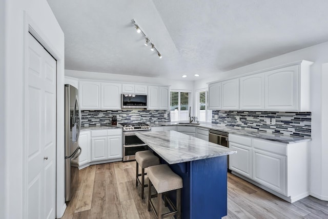 1308 S Drummond Rd, Spokane Valley, WA 99016 - kitchen featuring appliances with stainless steel finishes, a kitchen breakfast bar, white cabinets, a kitchen island, and a textured ceiling