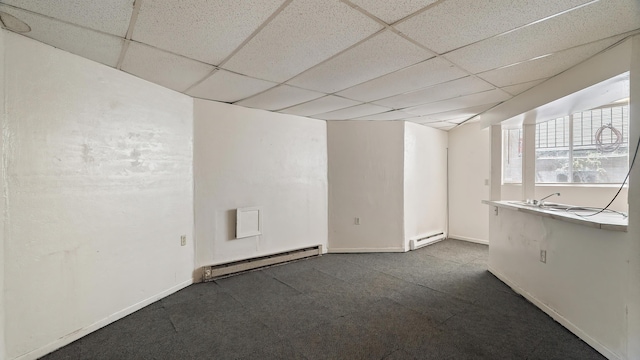 1622 W 10th Ave, Spokane, WA 99204 - empty room with baseboard heating, a drop ceiling, and dark colored carpet